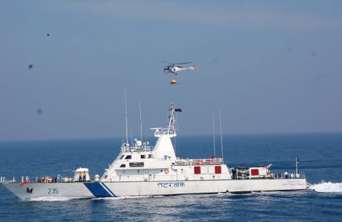Coast Guard helicopter using an oil spill disperser