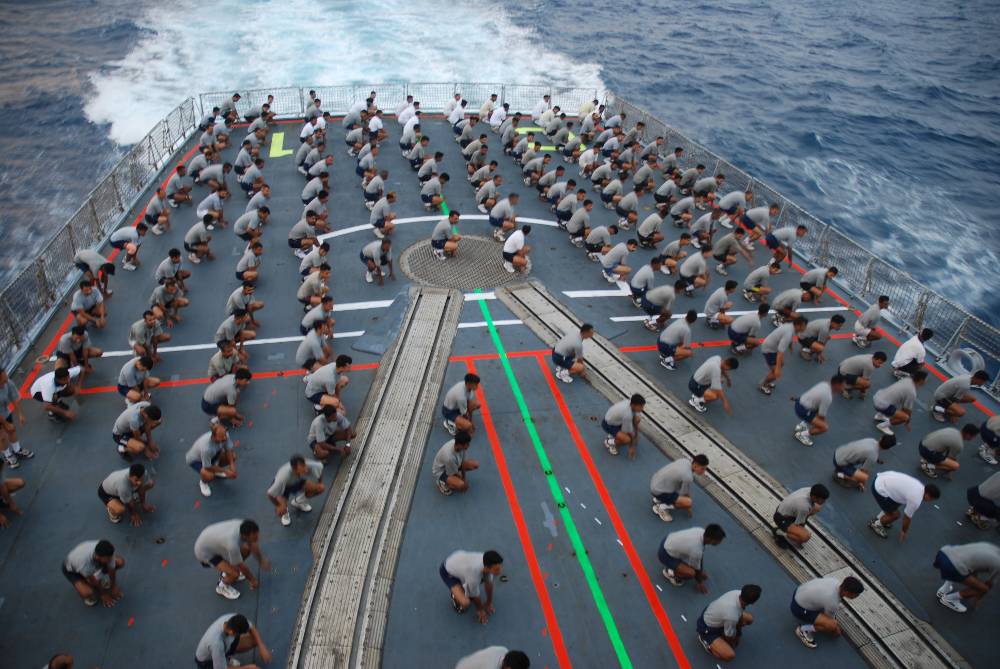 Naval personnel participating in Physical Training and Yoga on decks of ships at sea